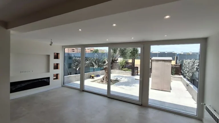 Interiorismo Sostenible: salón reformado con grandes ventanales y terraza