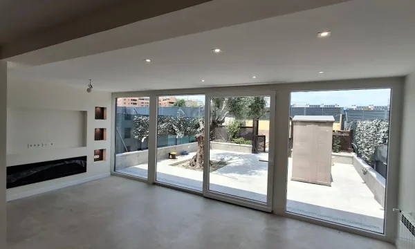 Interiorismo Sostenible: salón reformado con grandes ventanales y terraza